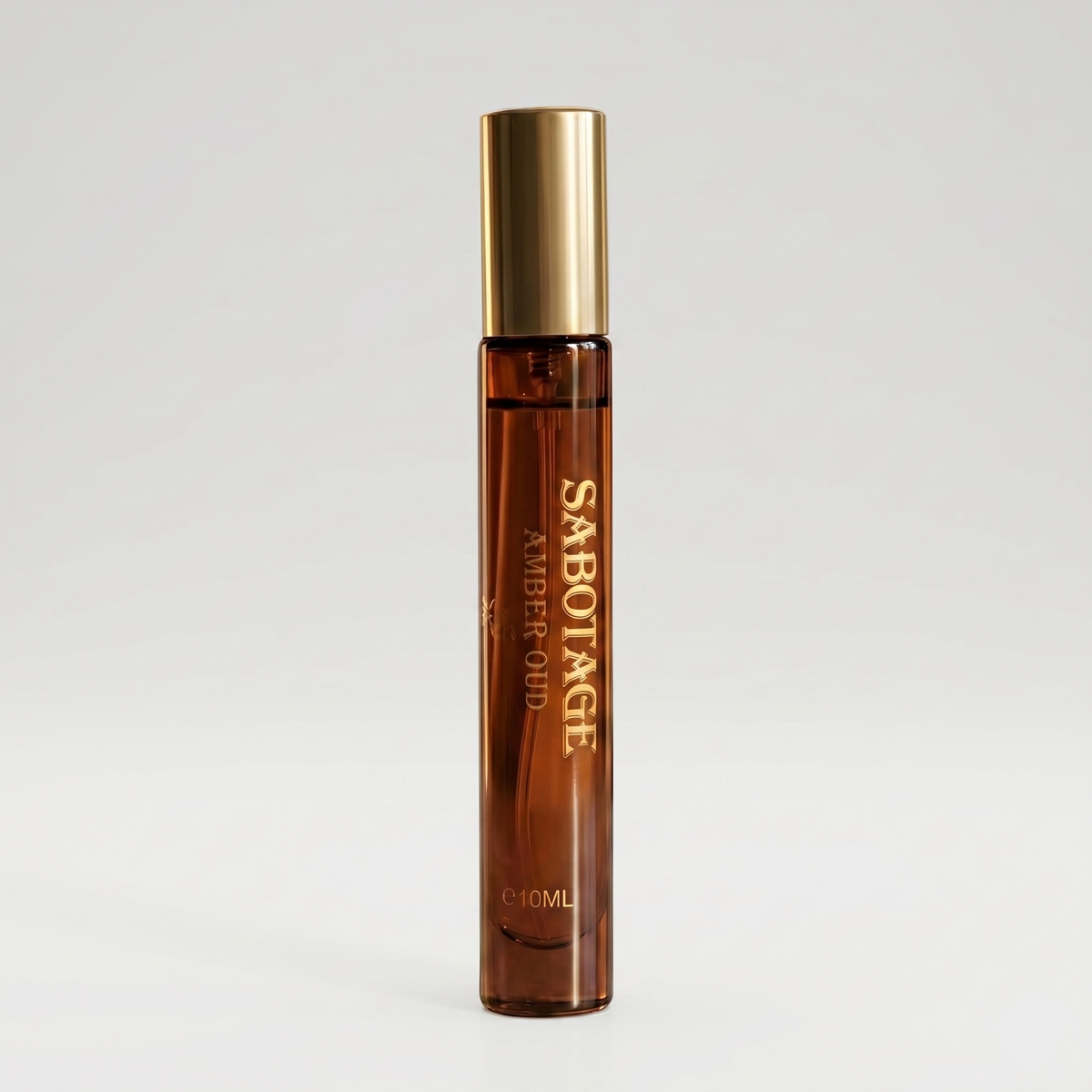 Front view of Sabotage Amber Oud 10ml travel spray perfume bottle with amber-toned fragrance oil, vertical gold lettering, and a metallic gold cap against a light background